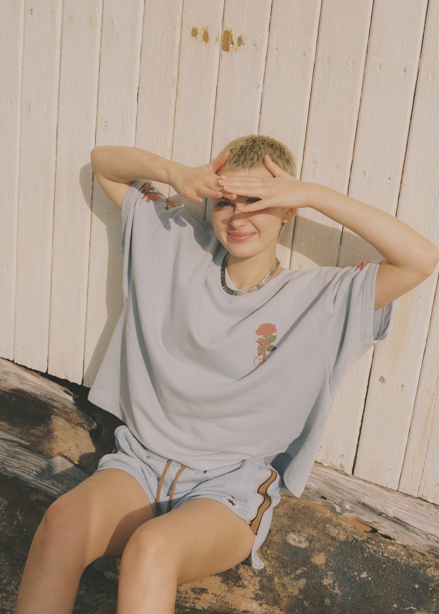 Person sitting on a wooden bench while wearing a light blue oversized t-shirt and matching blue shorts. 