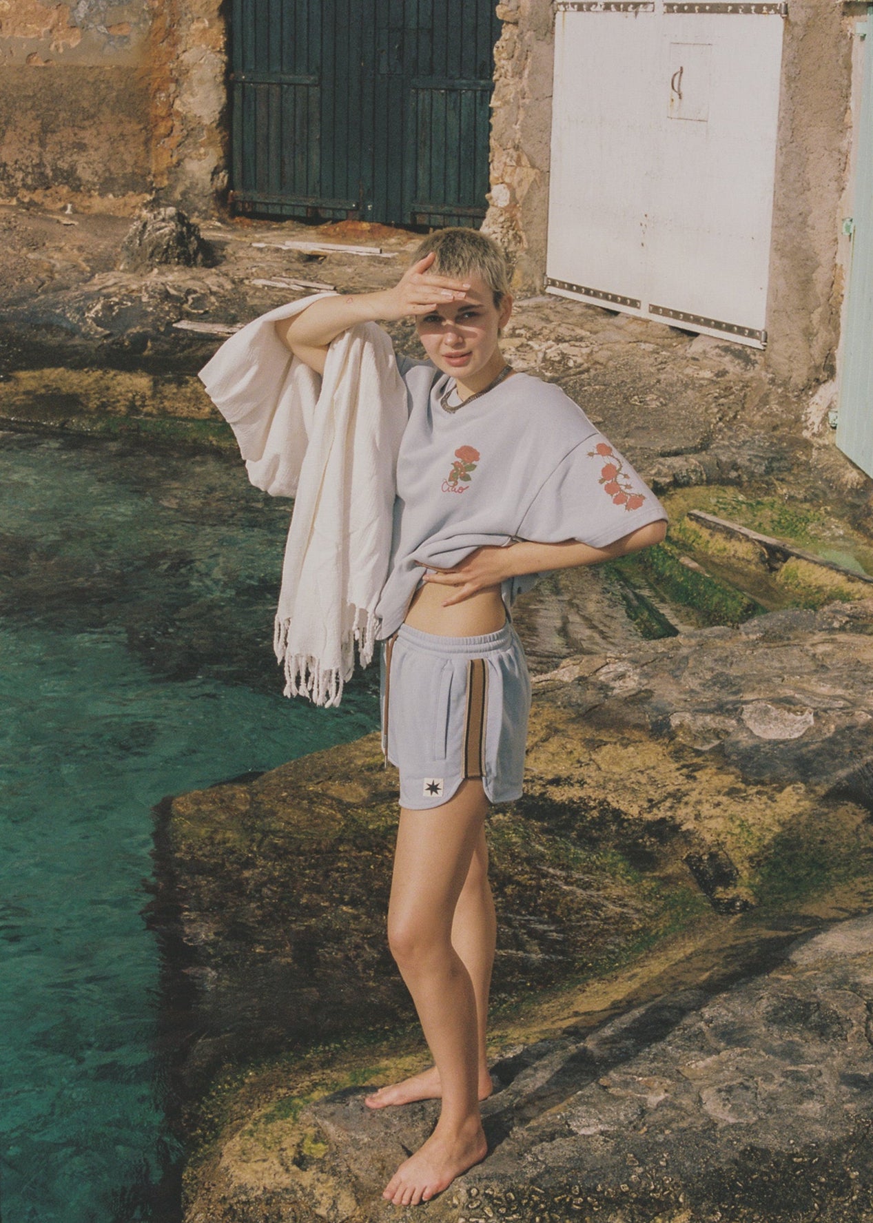 Person standing by a pool wearing matching light blue t-shirt and shorts set