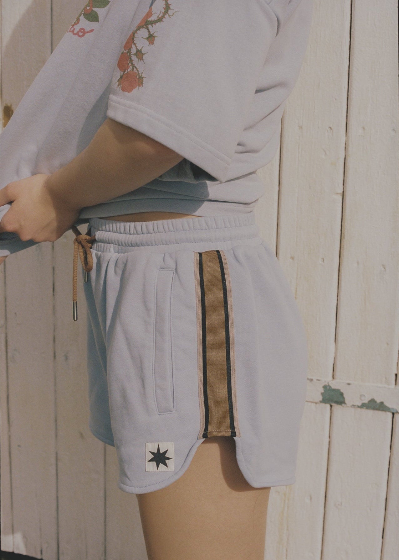 Person wearing light blue lounge shorts with a brown drawstring and branding