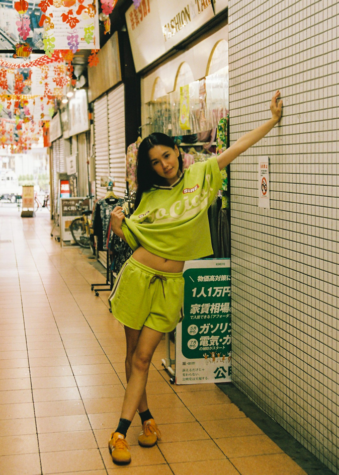 Woman in a bright green lounge jersey and drawstring shorts with CCV branding and logos