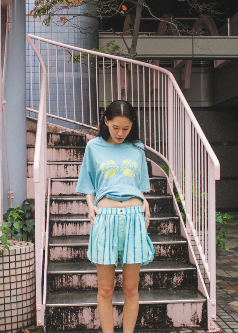 Woman in teal oversized t-shirt with a green crab graphic design and "Ciao Ciao" branding 