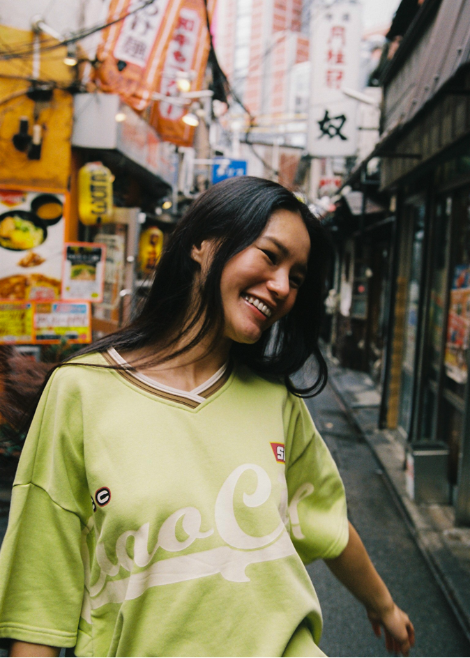 Woman wearing a bright green oversized jersey t-shirt with 'Ciao Ciao' text in Tokyo
