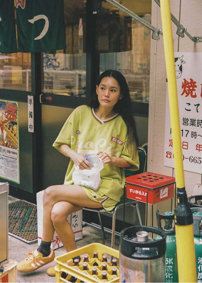 Woman wearing a bright green oversized jersey t-shirt with 'Ciao Ciao' text in Tokyo