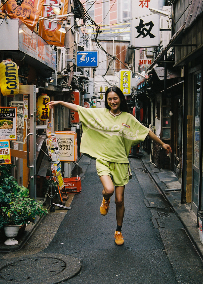 Woman wearing a bright green oversized jersey t-shirt with 'Ciao Ciao' text in Tokyo