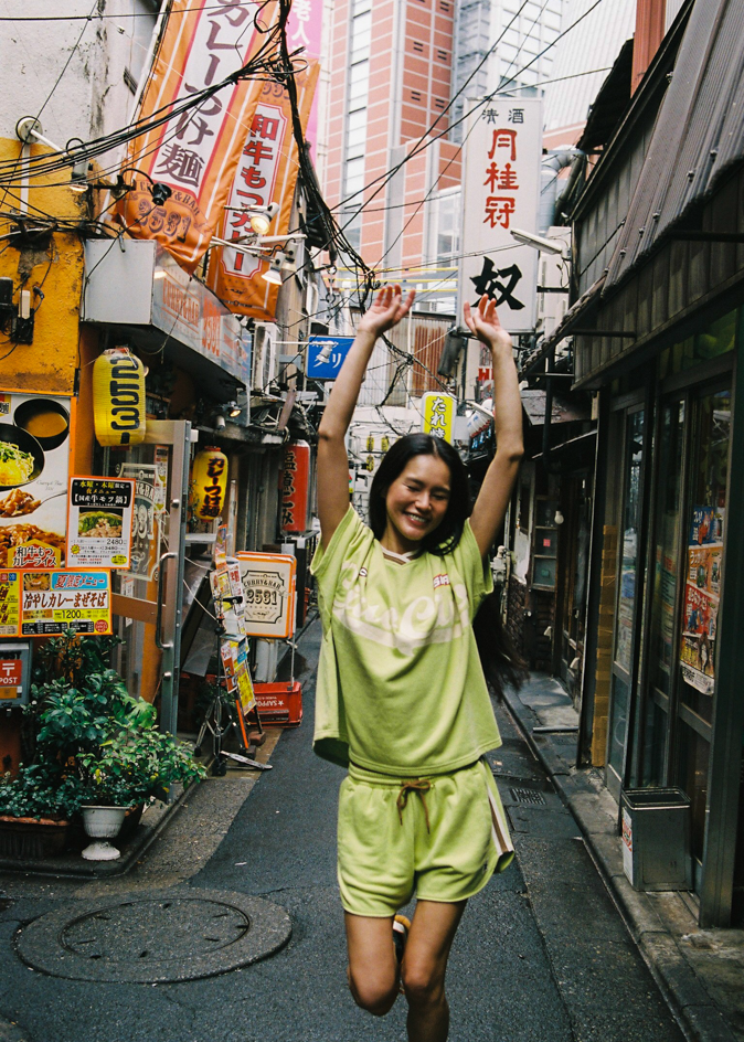 Woman wearing a bright green oversized jersey t-shirt with 'Ciao Ciao' text in Tokyo