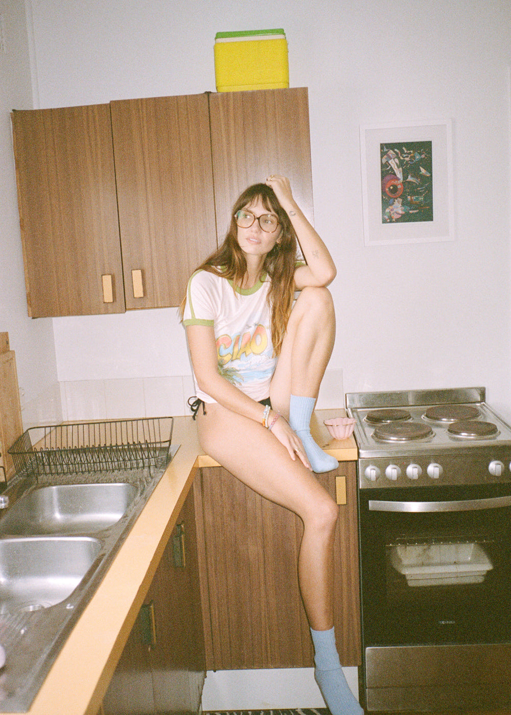 Person in a kitchen wearing a pink 'CIAO' ringer tee 