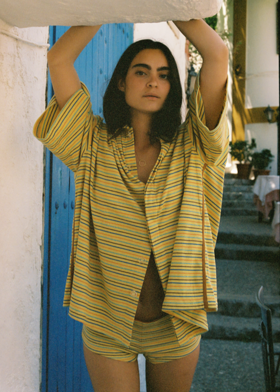 Wearing matching oversized striped yellow button up with mini shorts.