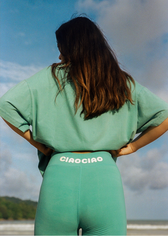 Woman in blue bike short with "CIAO" logo and blue oversized t-shirt on a beach 