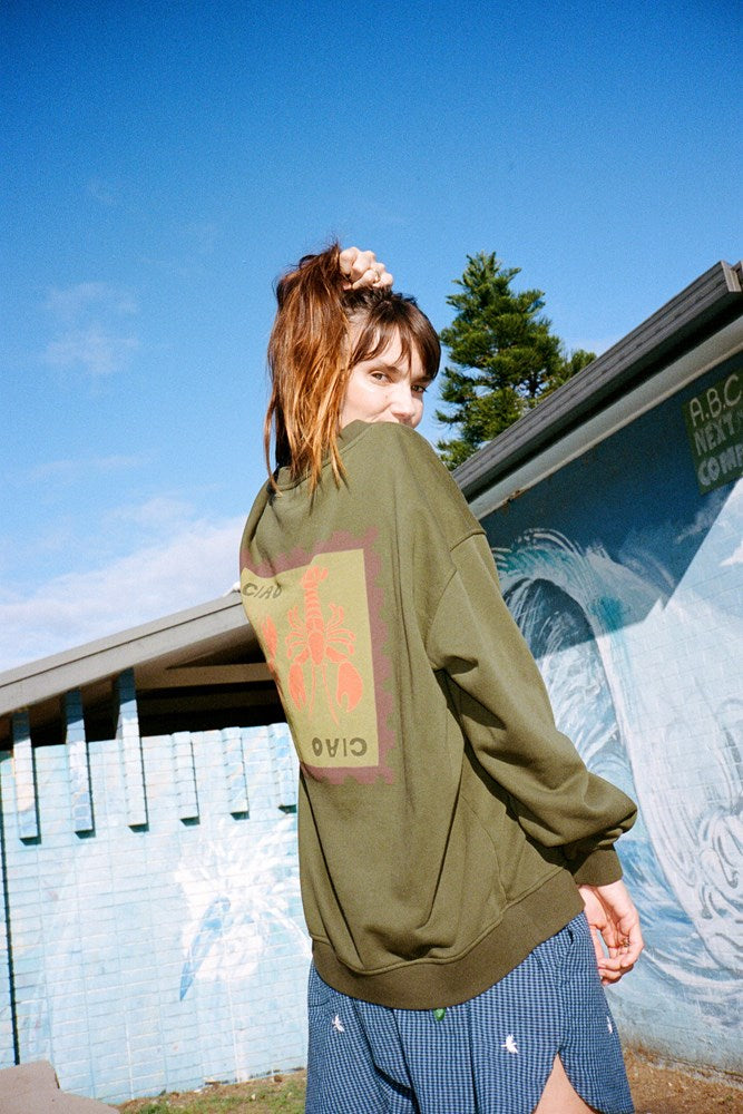 Person wearing a green jumper with an orange lobster graphic design 