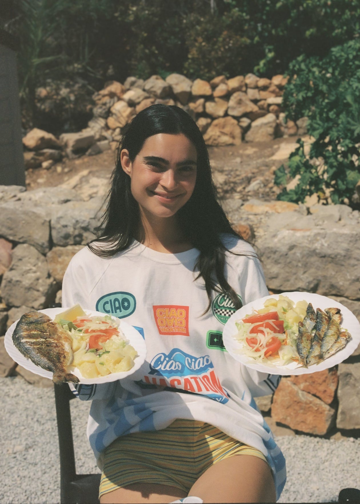 Woman wearing an oversized t-shirt with long sleeves and a pair of striped mini yellow shorts