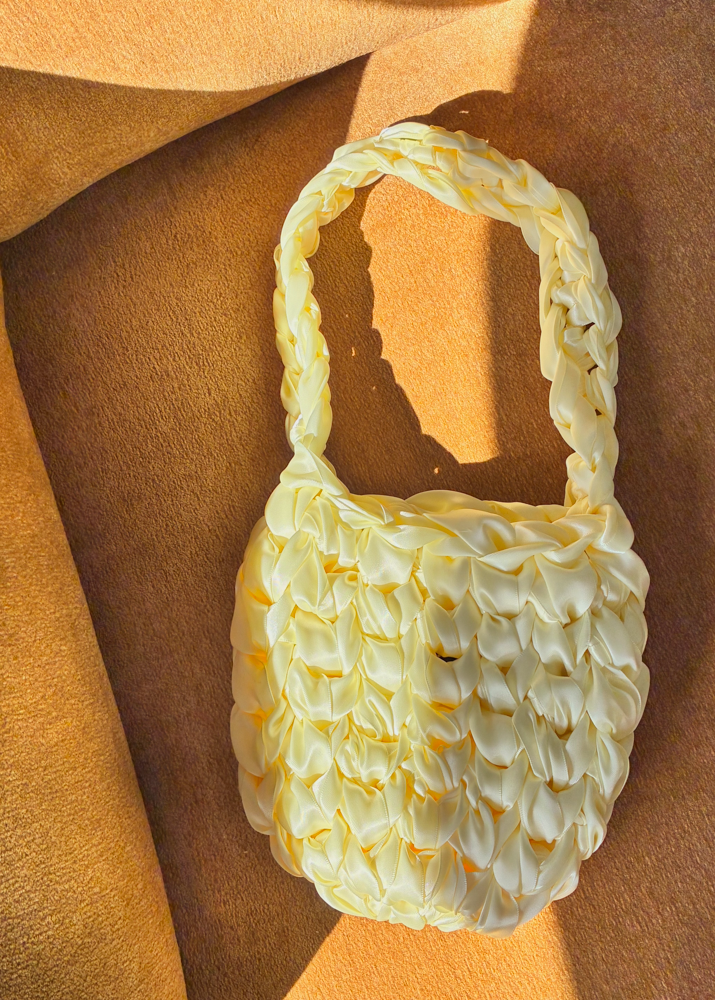 A light yellow satin knot woven shoulder bag