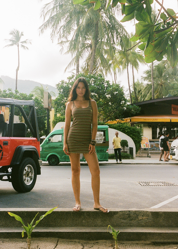 Woman wearing a brown dress with orange, yellow and green stripes and a CCV star logo in Thailand 