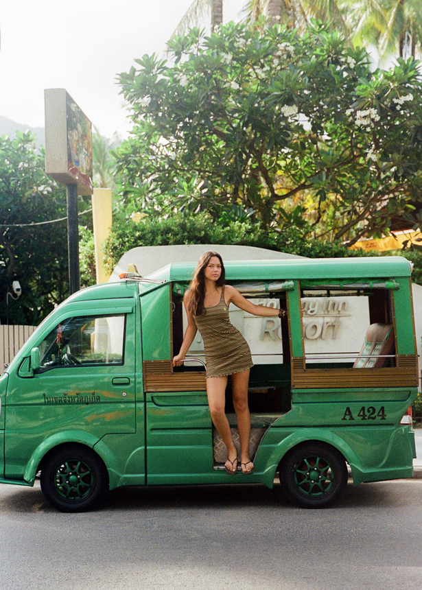 Woman wearing a brown dress with orange, yellow and green stripes and a CCV star logo in Thailand 