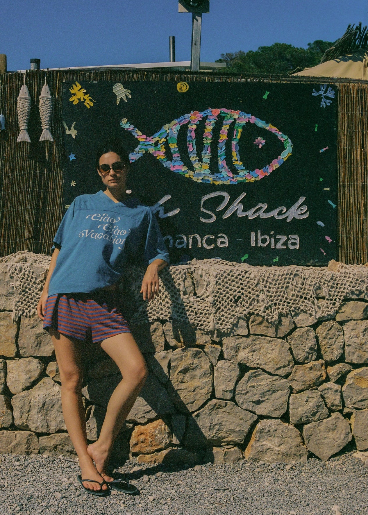 Person wearing a blue oversized t-shirt with a pair of striped shorts and black thongs